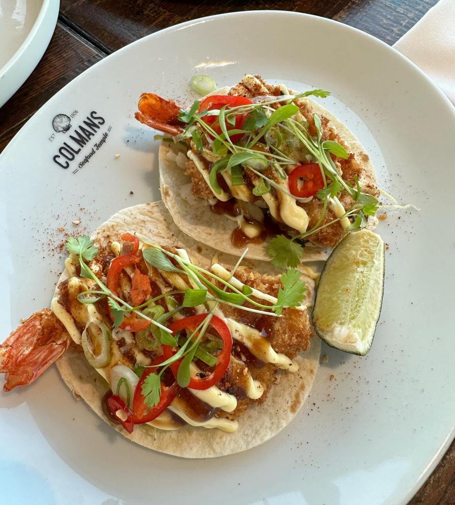 Deep fried shrimp tacos served with salad leafs, chopped chili and a wedge of lime and special sauce at colmans seafood temple, south shields