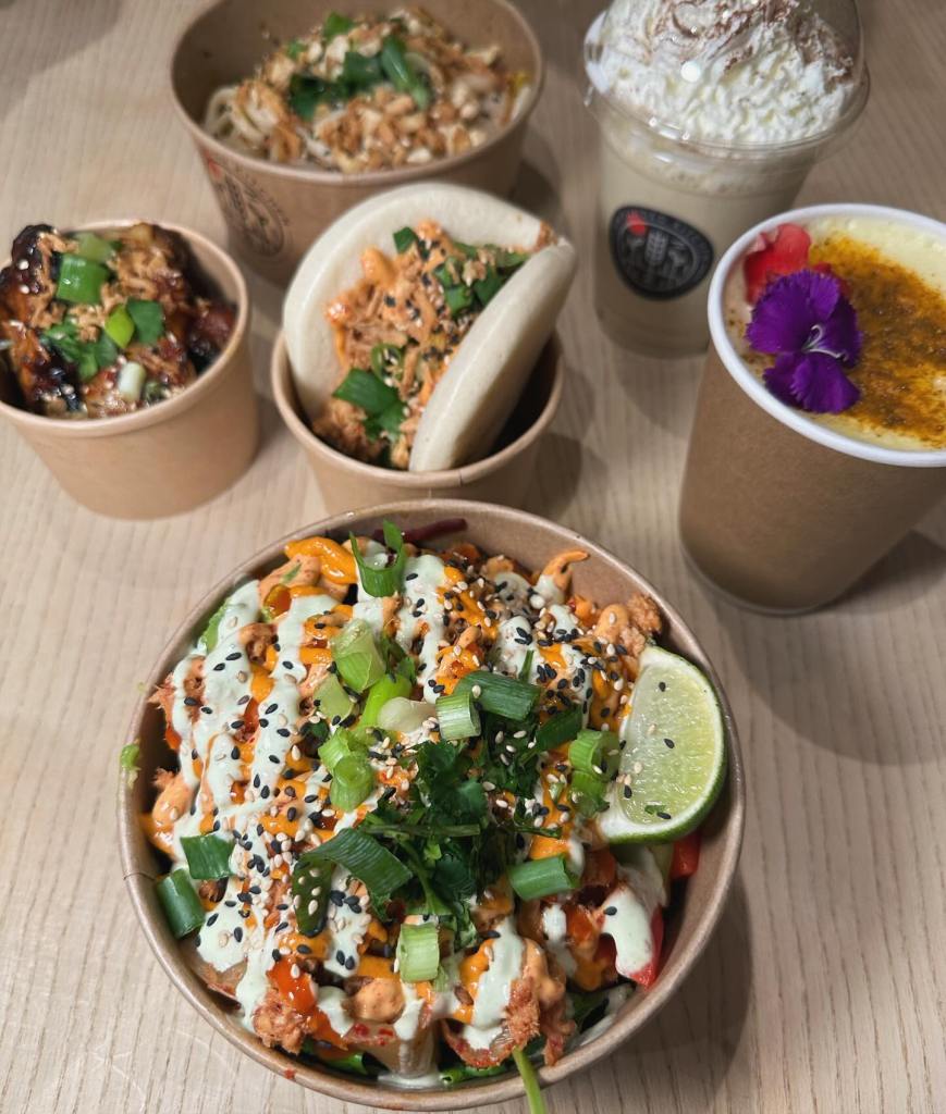 Turmeric latte with a flower garnish, Gochujang salmon bao bun and a prawn udon noodle bowl Korean wings and a salmon rice bowl. A table of colorful food perfectly presented with flowers at the grounded kitchen metrocentre gateshead