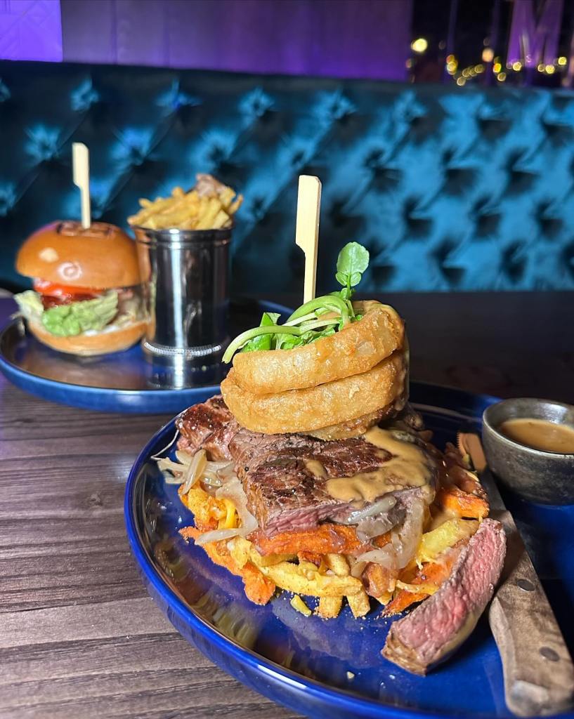 Steak and chips with peppercorn sauce and a veggie burger and chips served on electric blue plates and a bloody mary and prosecco