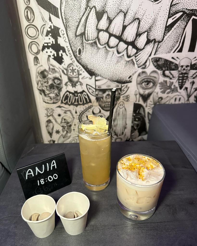 Honey Cake cocktail from Four Quarters, a creative drink with hazelnut, honey, and mascarpone, resembling a Christmas dessert in a glass along side two cups of quarter coins ready to play at the arcade