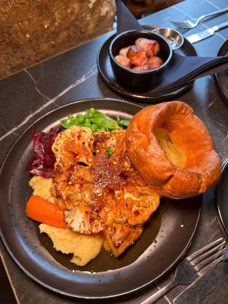 Cauliflower steak served with greens and roasted vegetables