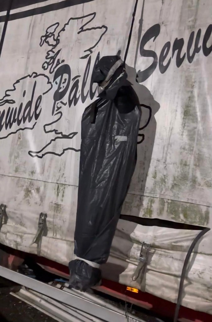 Spooky scary Halloween scene of a body bag hanging from a van