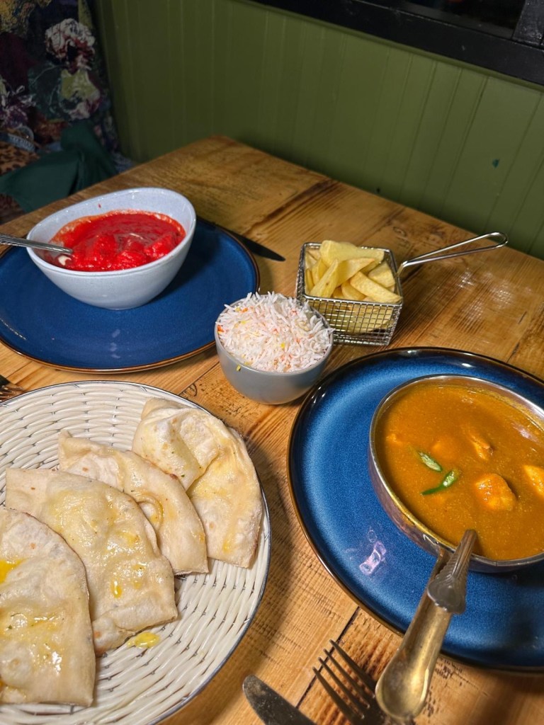 A vibrant spread of Madras and Masala dishes served with Pilau Rice and Garlic Nan at My Bombay Bistro