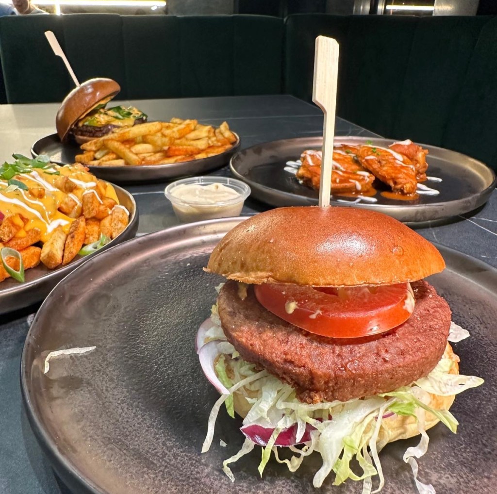 Vegan Cheese Drop A close-up of the Vegan Cheese Drop burger featuring a plant-based quarter-pounder patty, melted vegan cheese, lettuce, and Burger Drop's signature sauce, all inside a toasted brioche bun