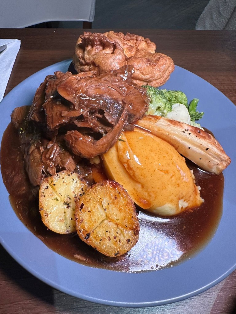 A hearty Sunday roast with tender topside of beef, Yorkshire pudding, crispy roast potatoes, buttery mash, and a medley of seasonal vegetables, topped with rich gravy