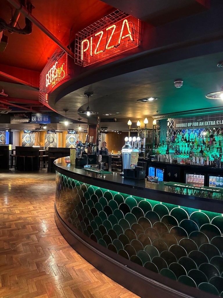 A warm bar with tones of wood, green and red creating an inviting and relaxed vibe