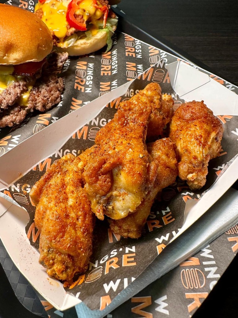 A vibrant plate of crispy chicken wings coated in a variety of sauces, including tangy lemon pepper, spicy buffalo, and smoky barbecue. Each wing is golden-brown, juicy, and glistening with flavor.