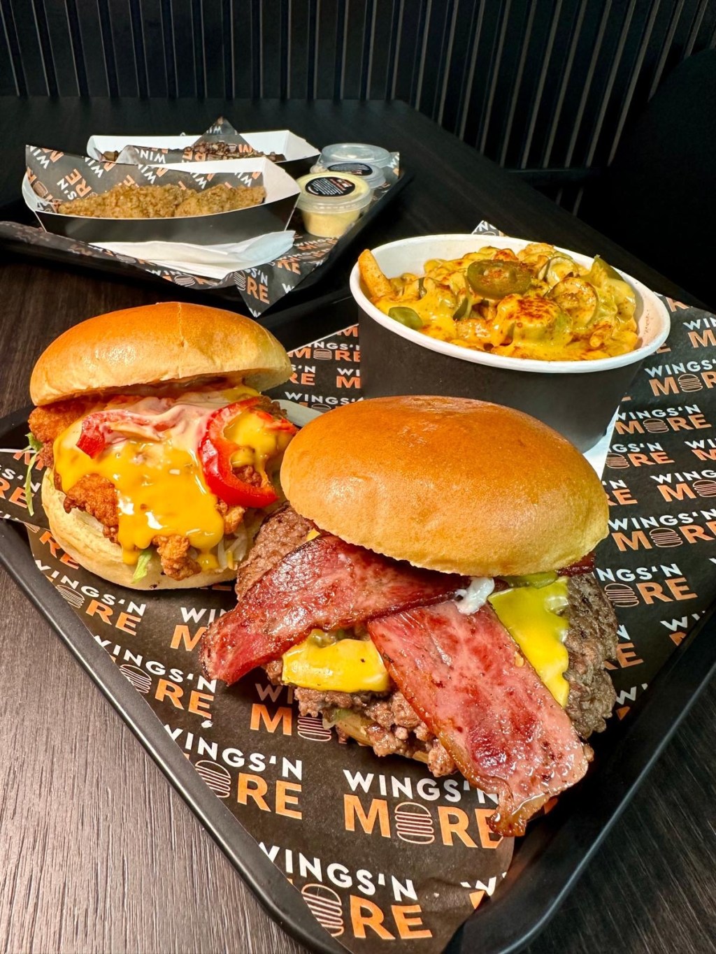 A stacked smash burger with a seared patty, crispy bacon, melted cheese, and drizzled with signature sauce, served in a soft brioche bun.