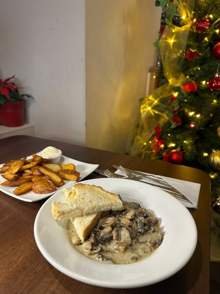 Two starter dishes at Rosa Twelve: golden potato skins with a creamy garlic dip, and garlic mushrooms in a light parsley sauce served with toasted bread