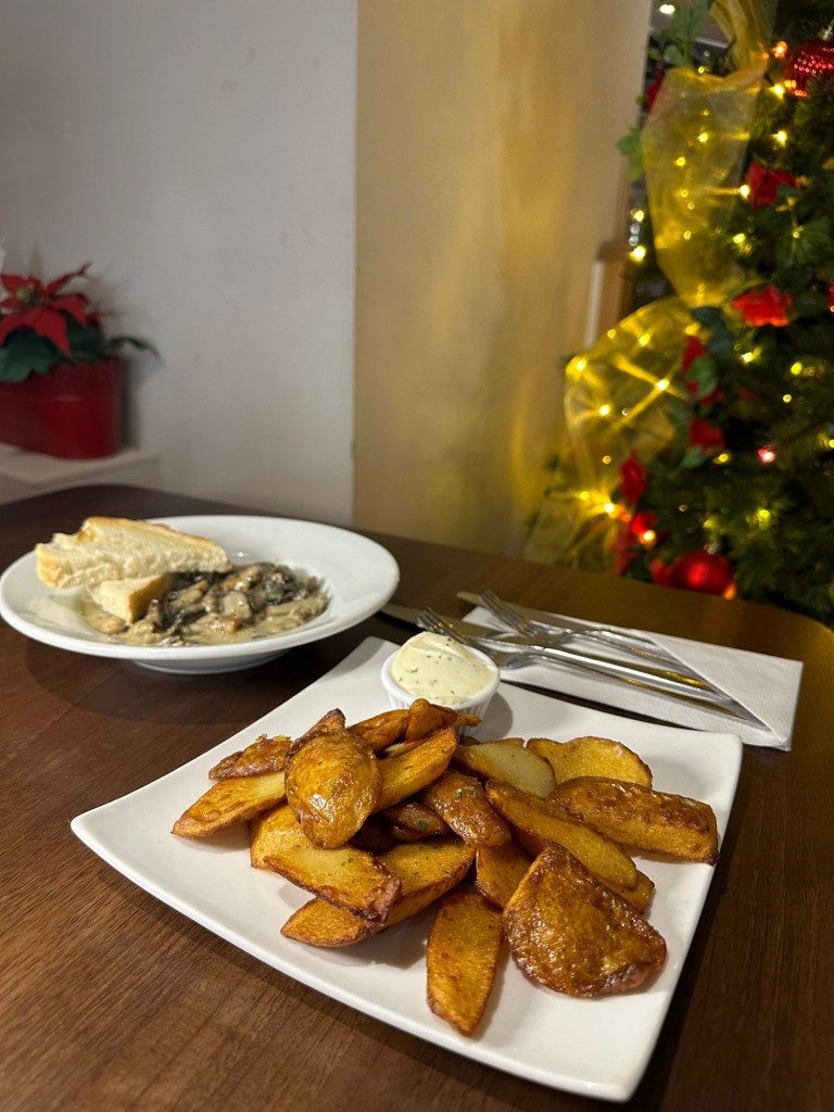 Two starter dishes at Rosa Twelve: golden potato skins with a creamy garlic dip, and garlic mushrooms in a light parsley sauce served with toasted bread
