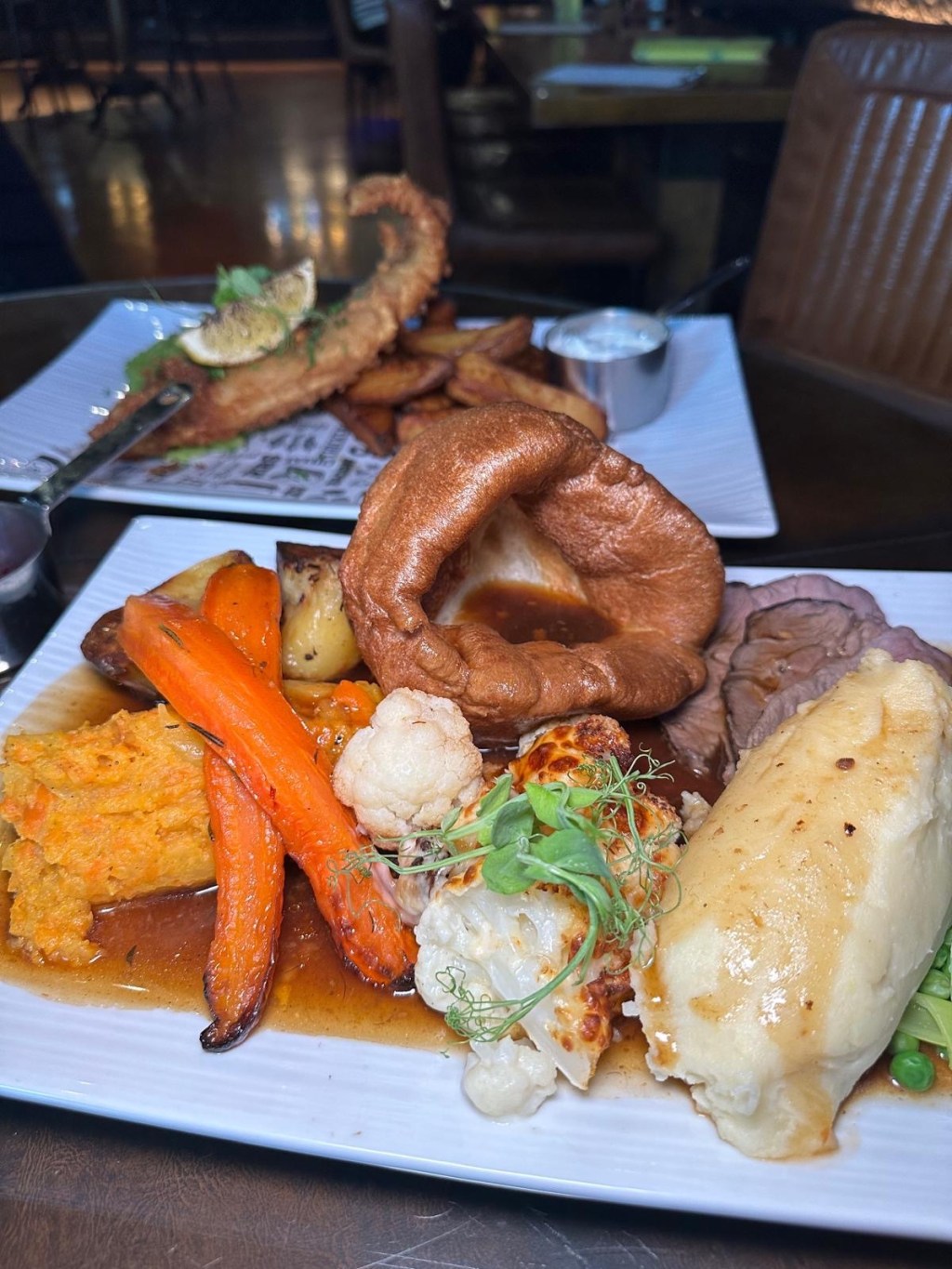 Slow Cooked Rump of Beef Tender slices of slow-cooked rump of beef served alongside buttery mash, crispy roast potatoes, carrot and swede mash, creamy cauliflower cheese, mixed greens, and rich, flavorful gravy.