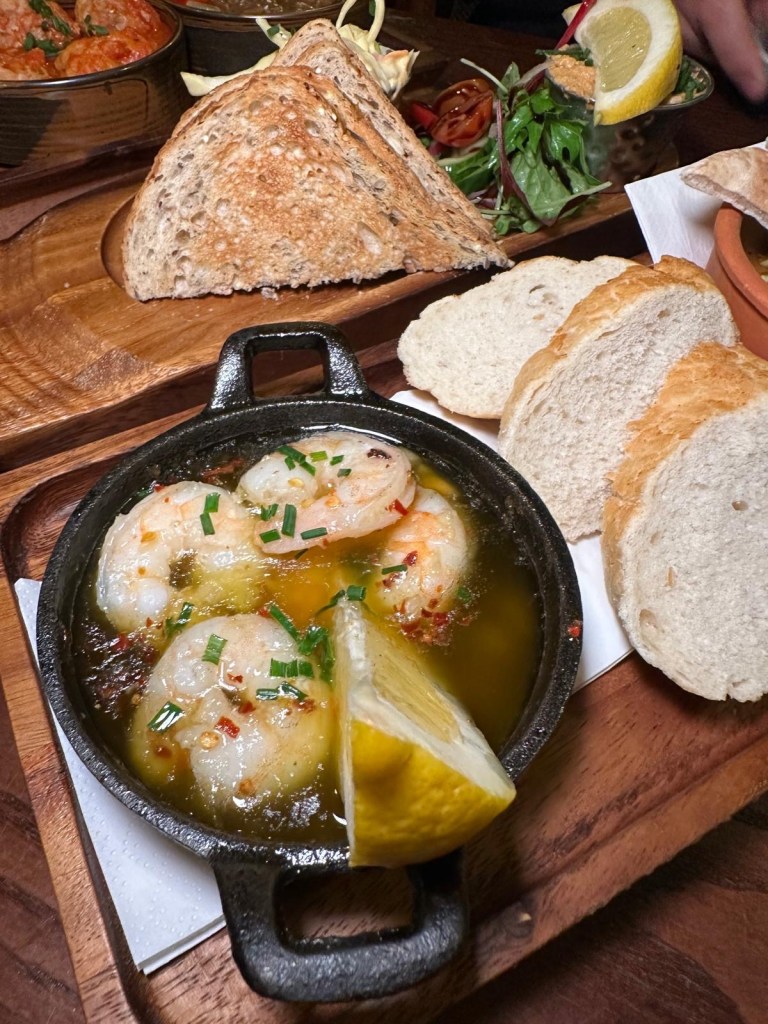 Gambas Pil Pil at The Spread Eagle, North Shields: A vibrant dish of Gambas Pil Pil with succulent prawns in a spicy chili and roasted garlic olive oil, paired with crusty bread for dipping