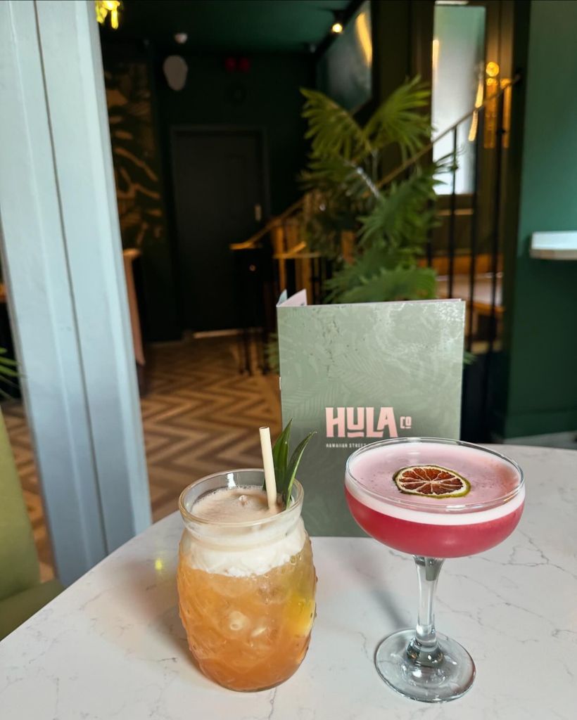 Mocktails at Hula, a pineapple shaped glass with a fruity drink and creamy foam. Also a red fruity drink in a margarita glass garnished with a dehydrated lime