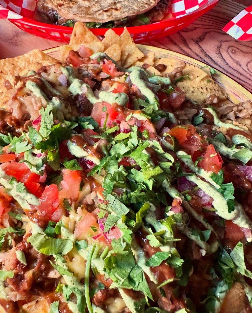 Loaded Nachos: A plate of loaded nachos piled high with melted cheese, fresh salsa, jalapeños, and guacamole.