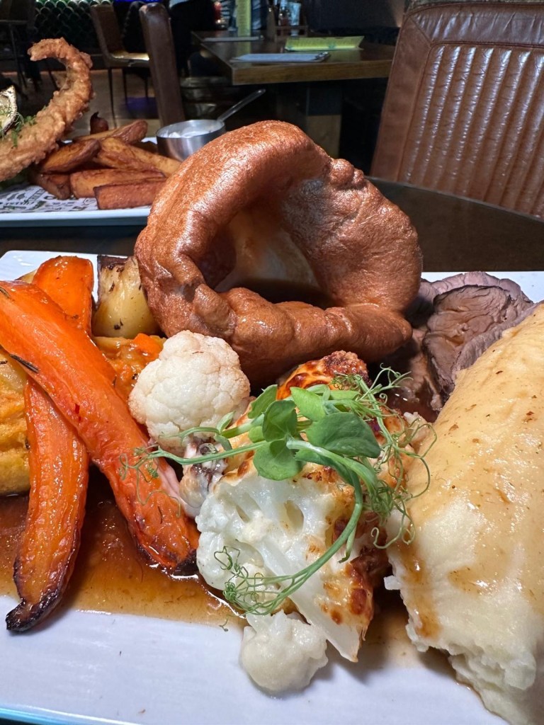 Slow Cooked Rump of Beef Tender slices of slow-cooked rump of beef served alongside buttery mash, crispy roast potatoes, carrot and swede mash, creamy cauliflower cheese, mixed greens, and rich, flavorful gravy.