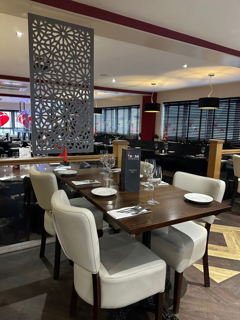 Cozy and elegant restaurant interior of Rosa Twelve, featuring softly lit dining tables, plush seating, and a warm, inviting atmosphere