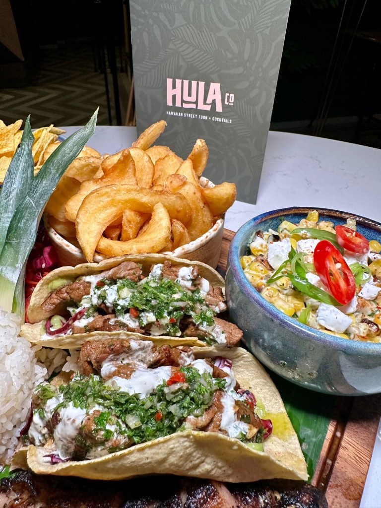 Steak Sharing Board: Tender birria strip loin steaks with steak tacos, chimichurri, pickled slaw, sticky rice, corn luu, and crispy potato sidewinders