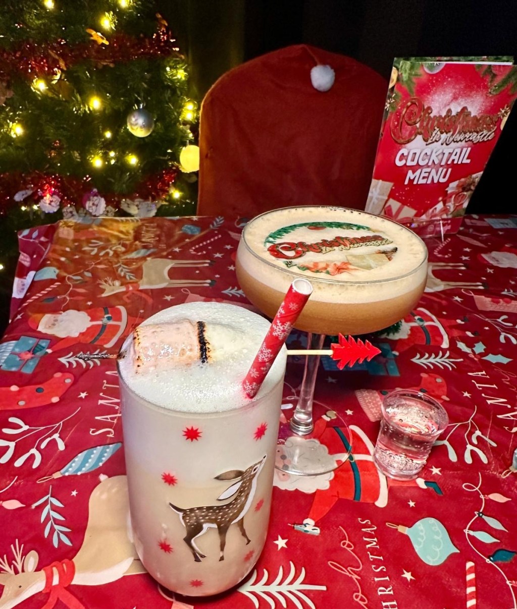 A Winter Spiced Pornstar Martini with a customized edible 'Christmas in Newcastle' design on top, sitting next to a festive backdrop. And an On Dasher cocktail, creamy and festive, served in a sleek glass, highlighted against Rusty’s retro Christmas decor.