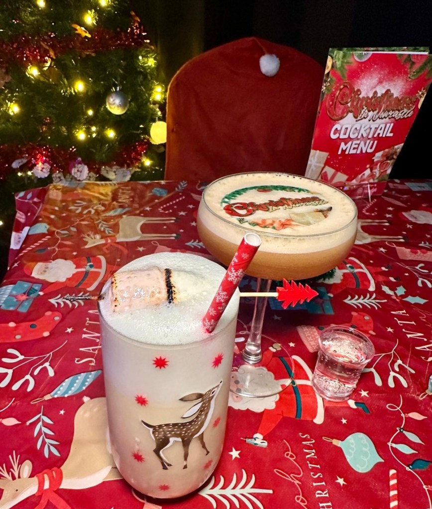 A Winter Spiced Pornstar Martini with a customized edible 'Christmas in Newcastle' design on top, sitting next to a festive backdrop. And an On Dasher cocktail, creamy and festive, served in a sleek glass, highlighted against Rusty’s retro Christmas decor.