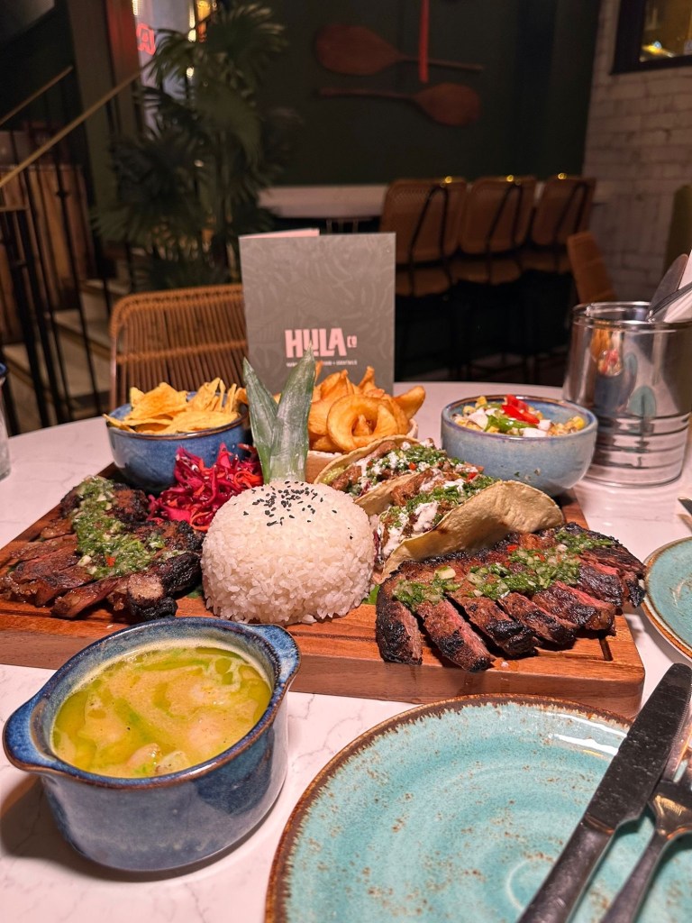 Steak Sharing Board: Tender birria strip loin steaks with steak tacos, chimichurri, pickled slaw, sticky rice, corn luu, and crispy potato sidewinders. Miso & Garlic Shrimp: King prawns in a rich garlic and miso emulsion with a touch of lime and coriander oil.