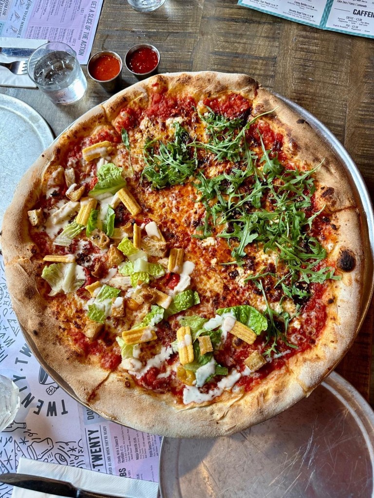 Huge 20-inch pizza at Twenty Twenty with a creative half-and-half topping of 'You Feta Believe It' and 'Hail Caesar