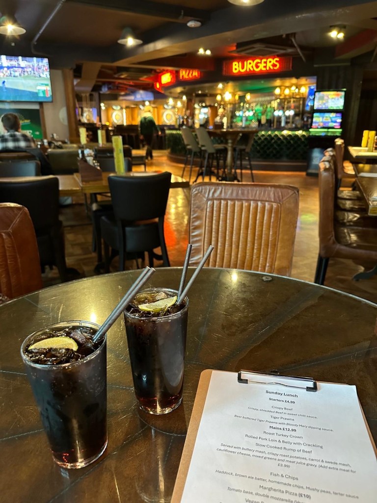 A warm bar with tones of wood, green and red creating an inviting and relaxed vibe