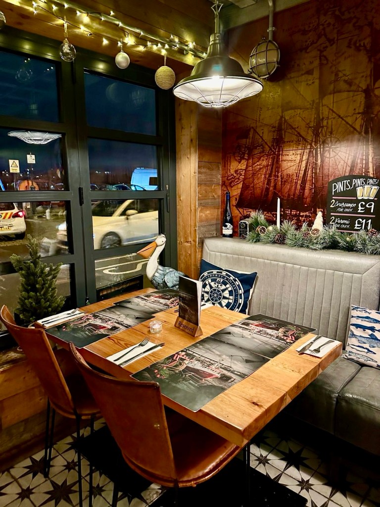 Intimate and cosy dining space at Dodgin’s Yard, featuring stylish decor with rustic wooden tables, warm lighting, and a riverside view perfect for a relaxed meal.
