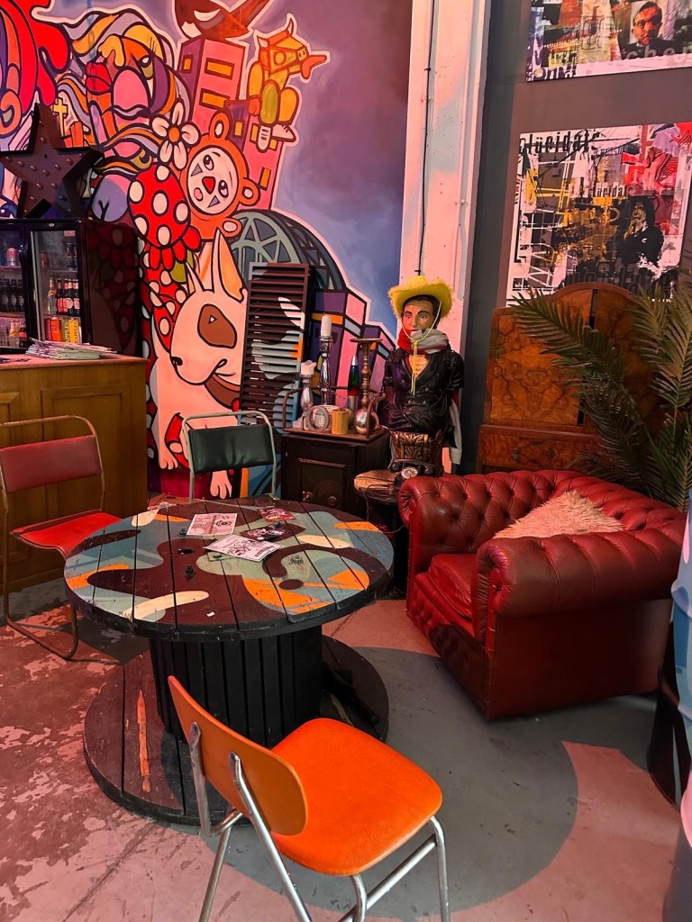 A vibrant and eclectic interior at The Loading Bay in North Shields, featuring colorful artwork, unique furniture pieces, and an inviting atmosphere perfect for enjoying Mediterranean-inspired meals.