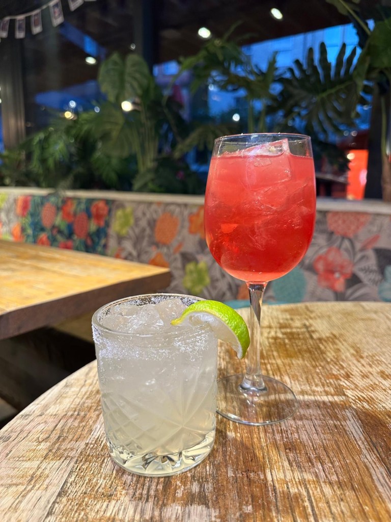 A colorful selection of festive cocktails from Revolution de Cuba, including a Merry Cherry Cuba Libre, Strawberry Margarita, and a shot tray with spicy mango and raspberry garnishes