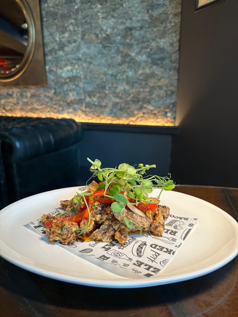 Crispy Beef. A plate of crispy, shredded beef coated in a glossy sweet chili sauce, served as a savory and tangy starter.