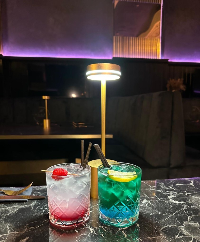 Lychee spritz cocktail served in a tall glass with ice and a garnish of mint and lime. Vibrant energy drink mocktail served with colorful citrus garnishes