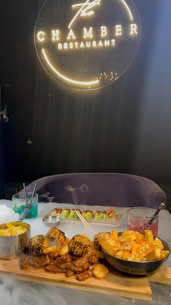 Surf and turf dish featuring grilled prawns, tender steak, seasoned chips, mac n cheese, and charred sweetcorn.