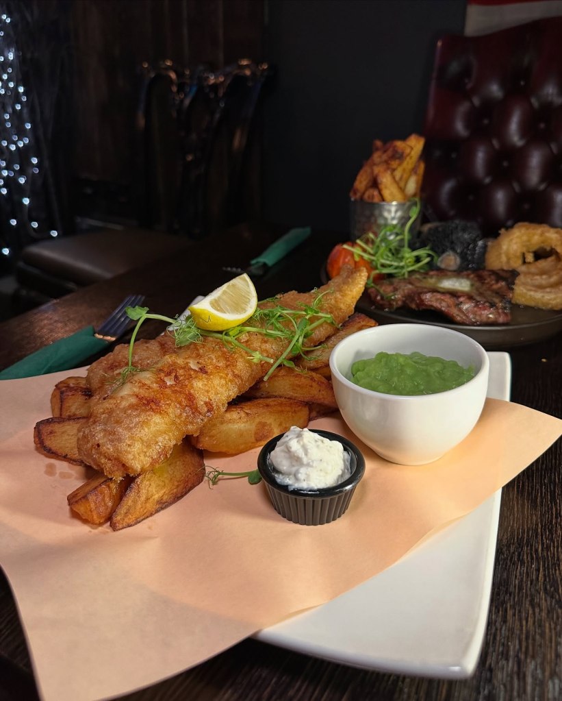 Golden fish and chips at Sticky Wicket, served with chunky chips, mushy peas, and tangy tartar sauce