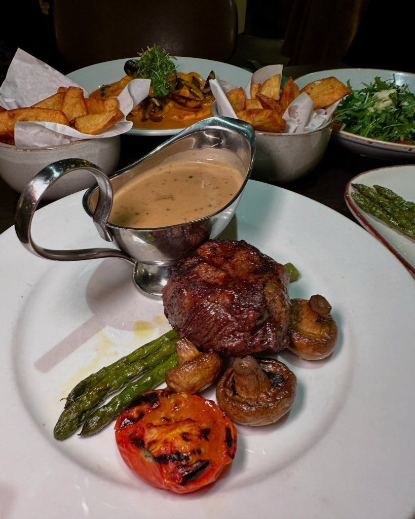 Medium-rare steak served with asparagus, mushrooms, grilled tomato, and a rich peppercorn sauce at Fabio’s Italian Restaurant.