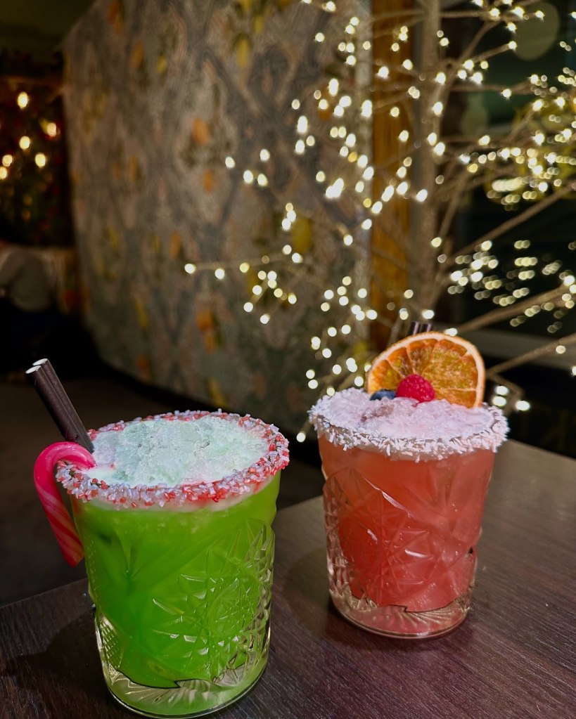 Festive cocktails, including the vibrant green Mr. Grinch and the tropical Merry Mai Tai, served with seasonal garnishes at Fabio’s Italian Restaurant.