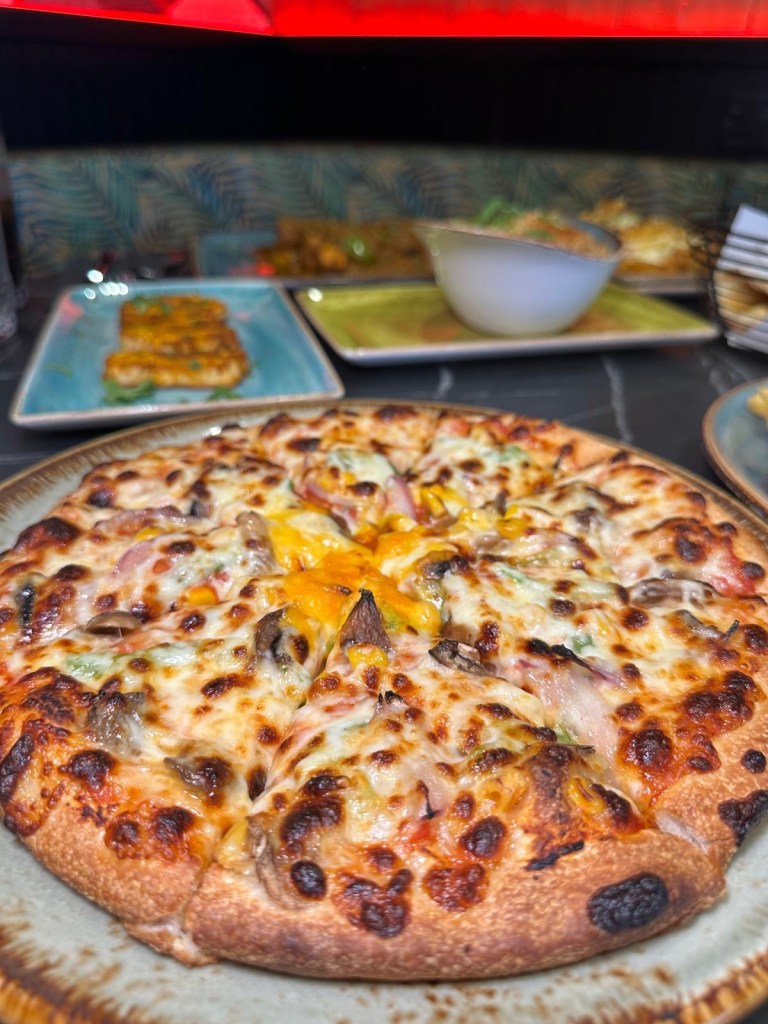 A freshly baked vegetarian pizza loaded with colorful vegetable toppings, melted cheese, and a side of garlic mayo