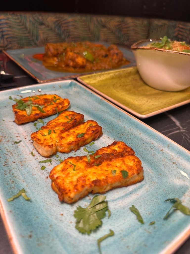 Golden grilled halloumi slices served on a white plate with a garnish of fresh herbs
