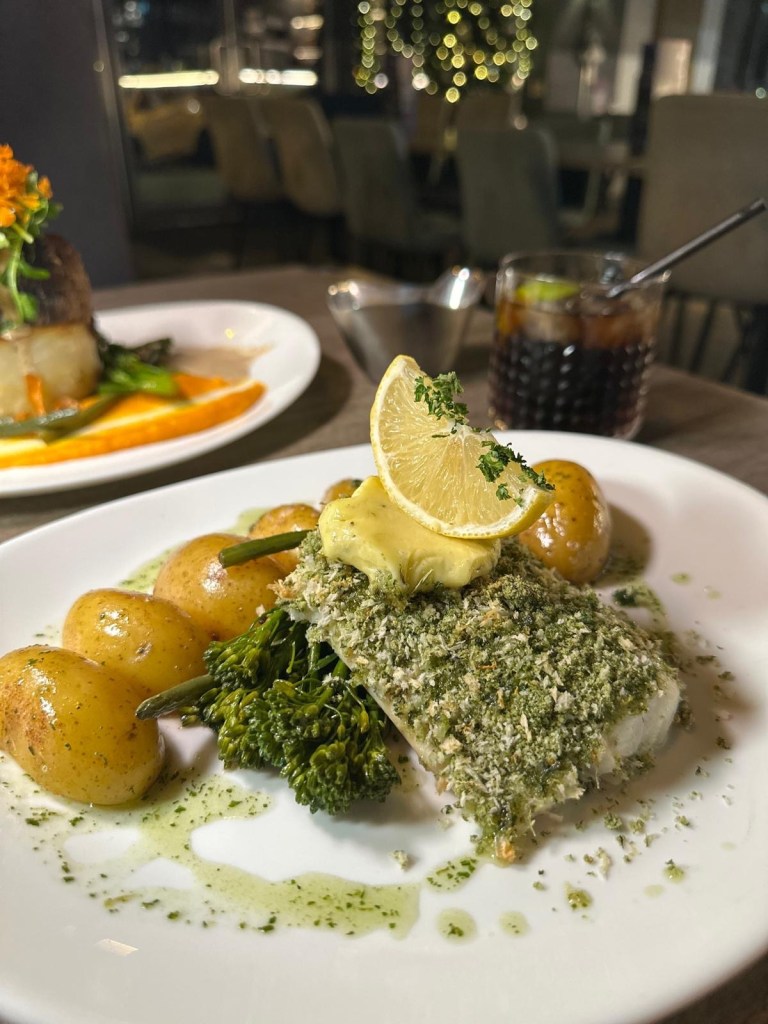 Herb-crusted cod loin served with new potatoes and buttered greens at Breeze Lounge