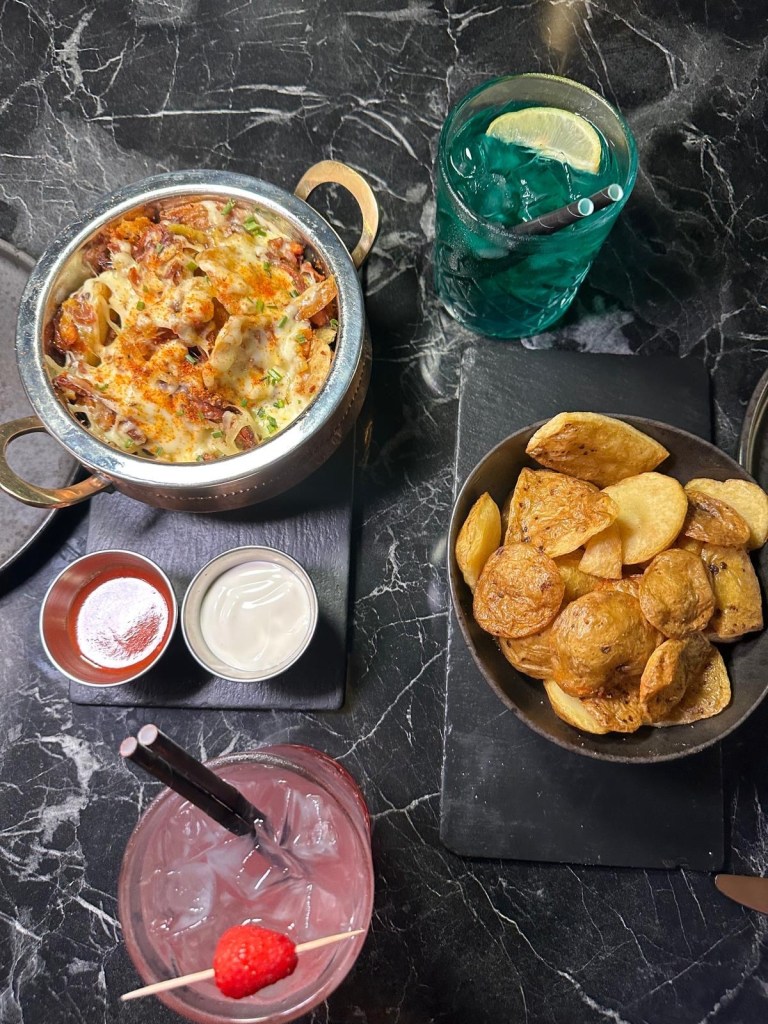 Unique onion bhaji potato skins garnished with fresh herbs and served with dipping sauce.