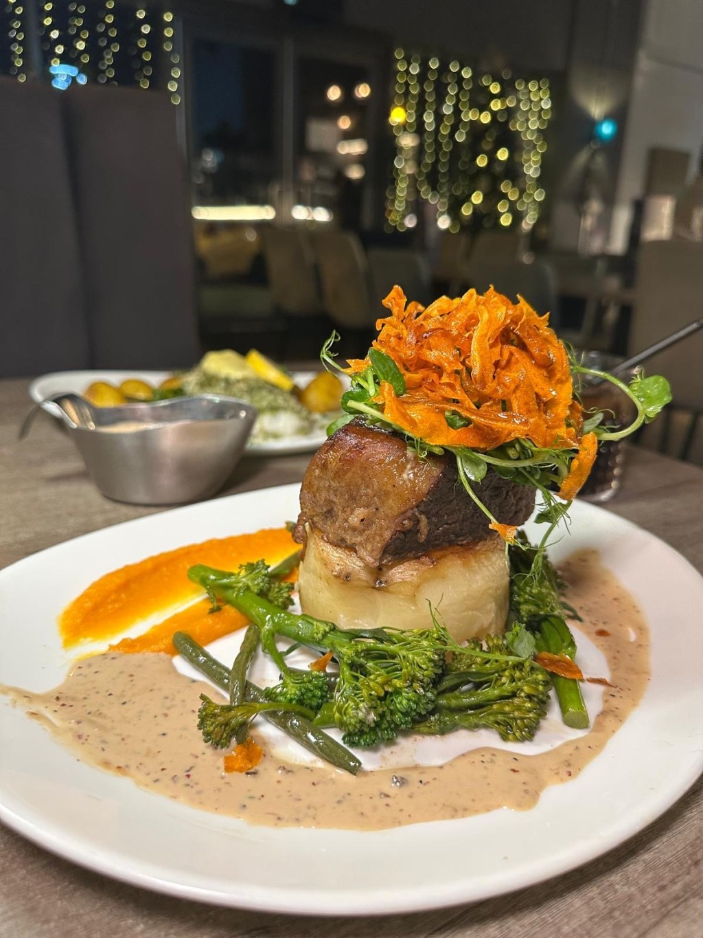 Slow-cooked beef with fondant potato, buttered greens, and peppercorn sauce at Breeze Lounge