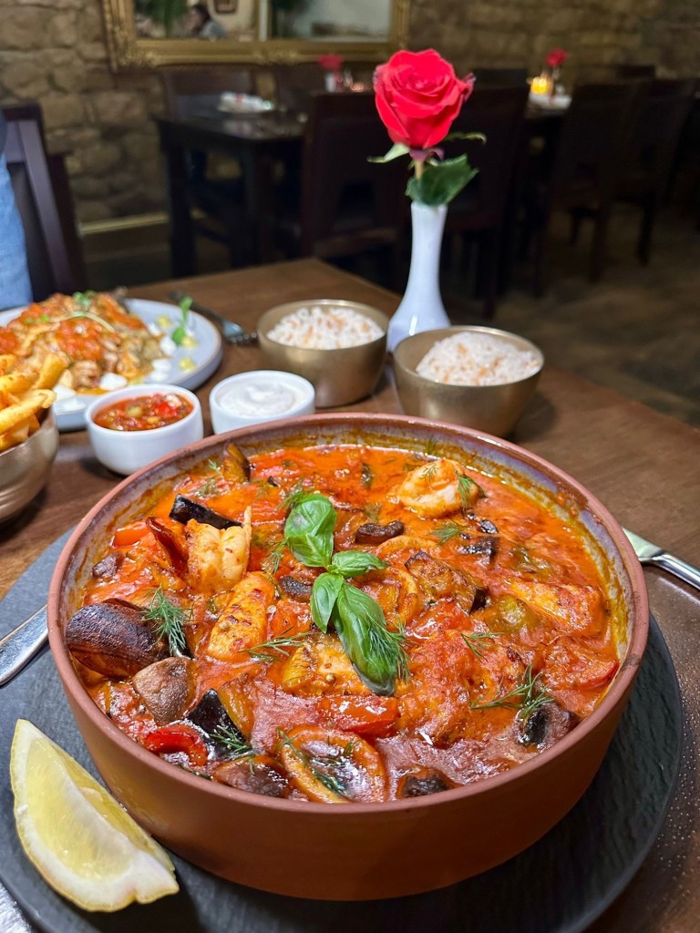 A steaming seafood casserole with prawns, mussels, squid, and salmon, baked in a creamy tomato-garlic sauce, served in a rustic clay pot.