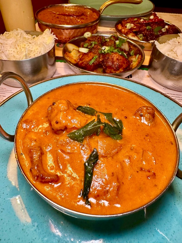 A plate of South Indian Fish Curry, with tender fish in a creamy coconut sauce, garnished with herbs