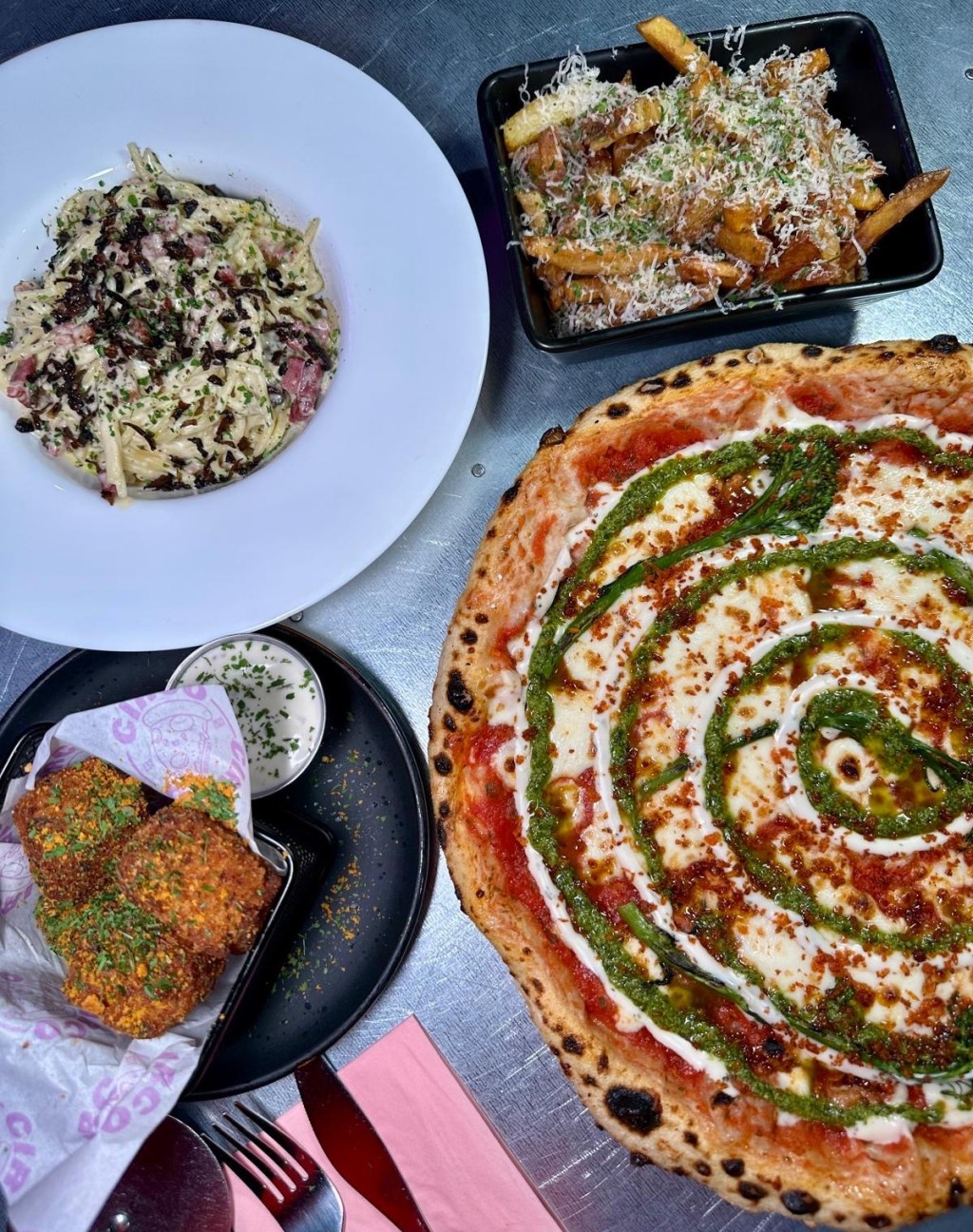 A table spread of savory dishes at Circo Italian, including Fungi Truffle Pasta, Pezzorella Pizza, Mac & Cheese Bombs, and Truffle Fries
