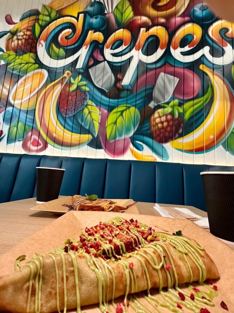 A beautifully presented sweet crepe with Sicilian pistachio spread, crushed pistachios, fresh strawberries, and a sprinkle of raspberry flakes.