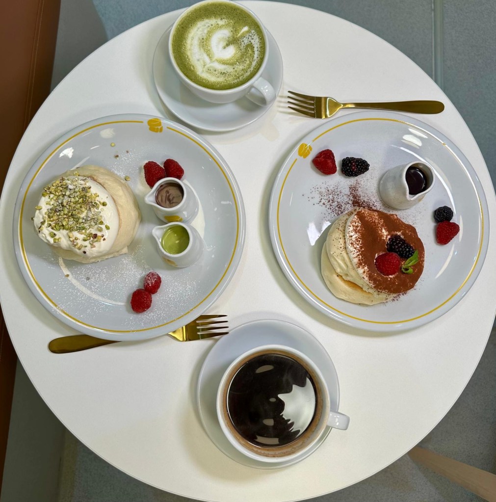 A spread of Fluffy Fluffy’s soufflé pancakes, including pistachio and tiramisu flavors, paired with matcha latte and Americano