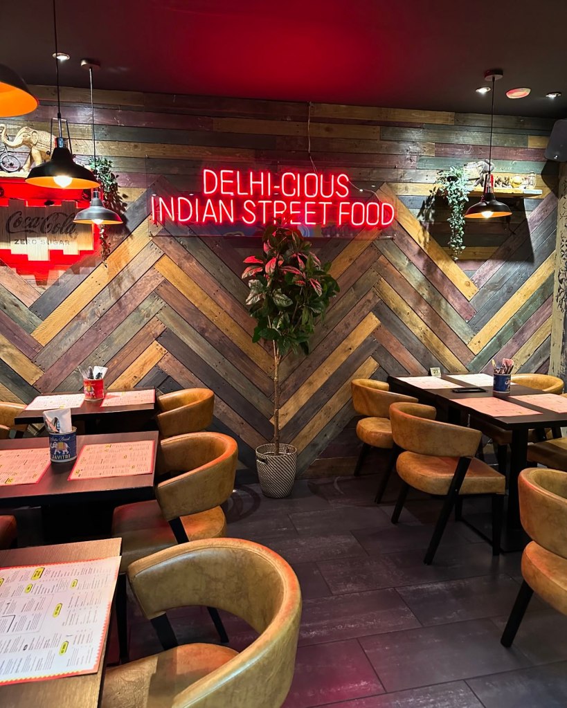 A cozy corner in My Delhi’s Newcastle branch, with neon signs and colorful murals inspired by Indian street art.