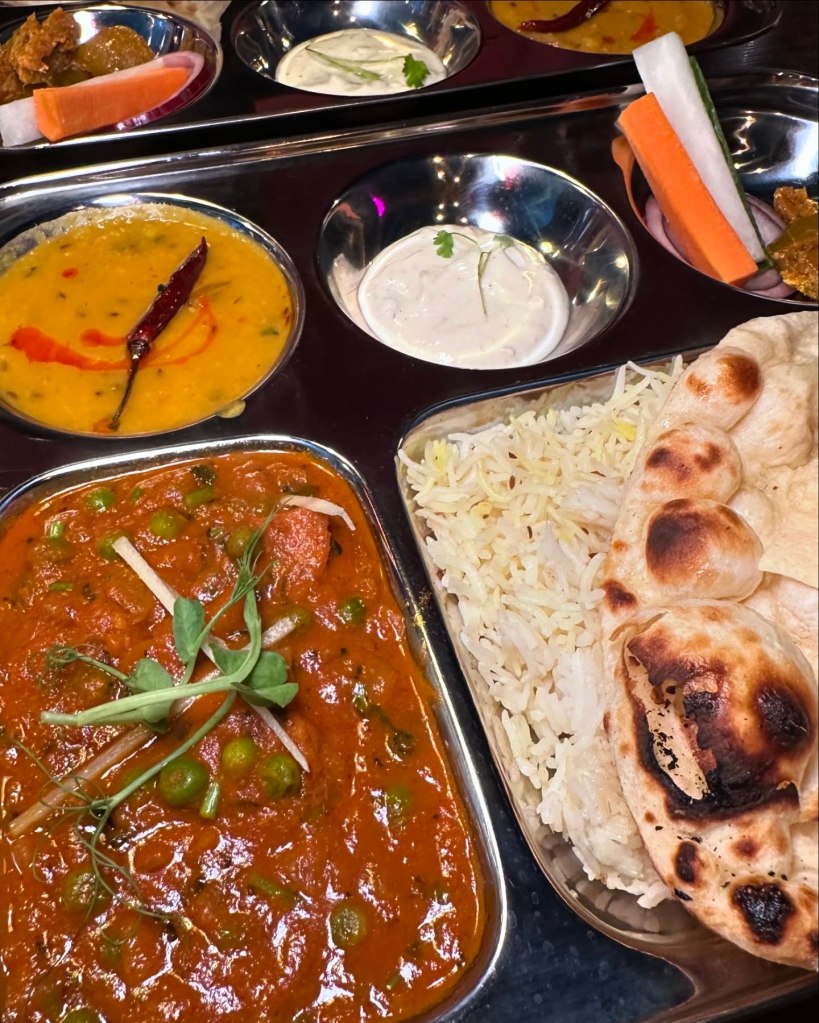 A colorful Canteen Thali Tray, with curry, rice, naan, Indian salad, and dal, beautifully plated