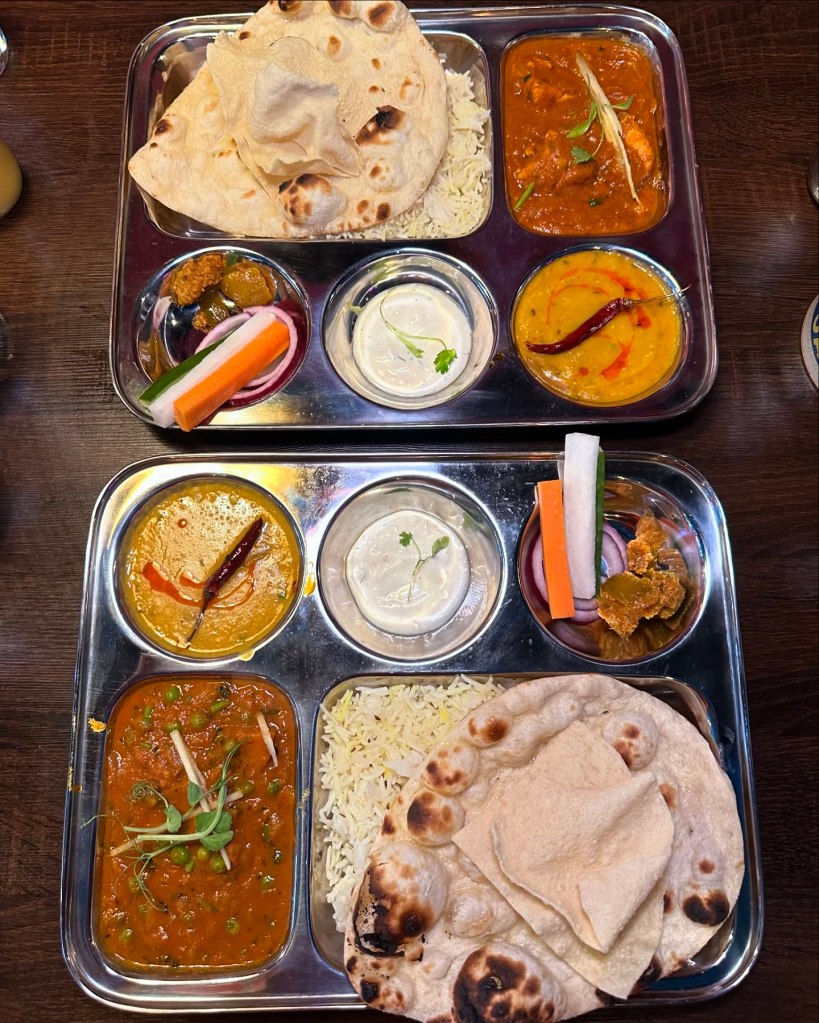 A colorful Canteen Thali Tray, with curry, rice, naan, Indian salad, and dal, beautifully plated