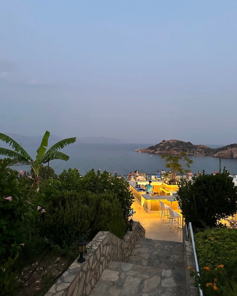 Breathtaking view from TUI Blue Seno overlooking the turquoise coast with a picturesque island on the horizon, framed by the golden hues of a Mediterranean sunset.