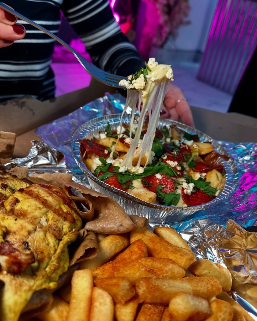 Hot honey-loaded chips topped with melting mozzarella, feta, pepperoni, and parsley, served in a takeaway box